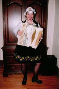 Emily Milling - Producer, Composer, playing an accordion dressed in traditional German attire