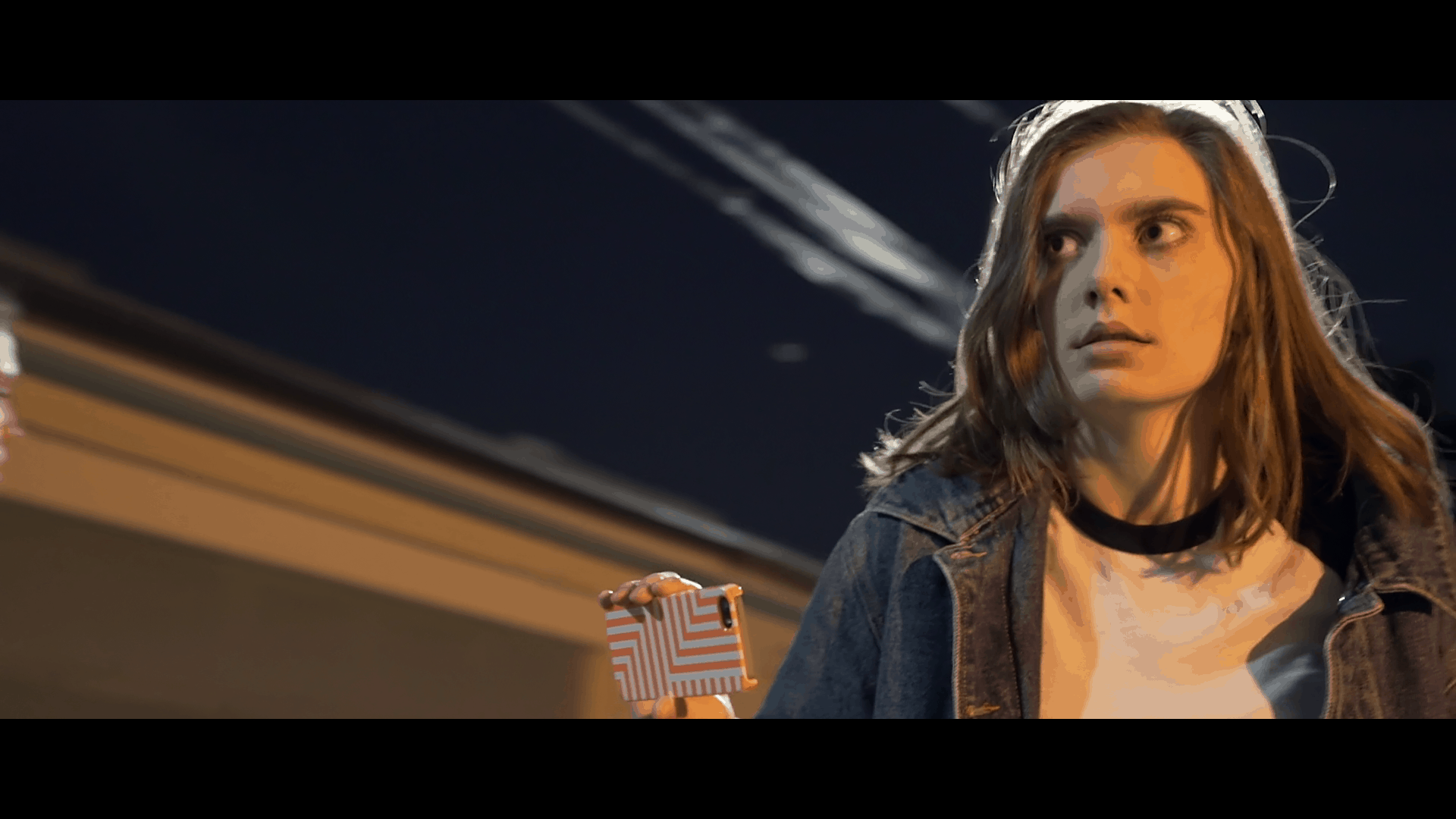 Impossible Horror Reviewed by the Mind Reels Lily (Haley Walker) searching for the scream in an alleyway holding an iphone wearing a denim coat
